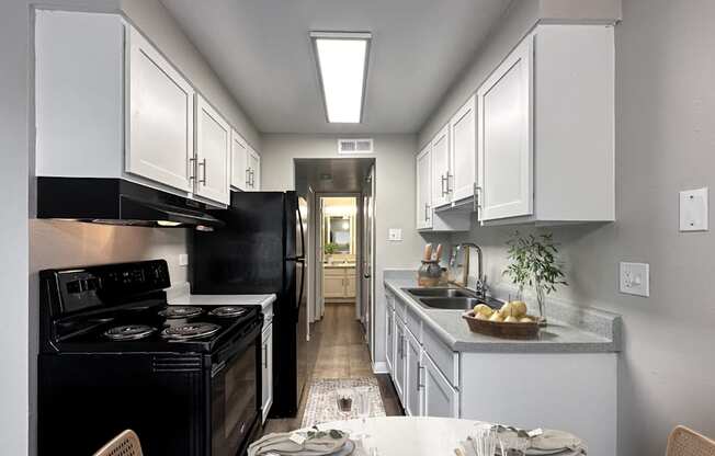 A kitchen with a black stove top oven and white cabinets.