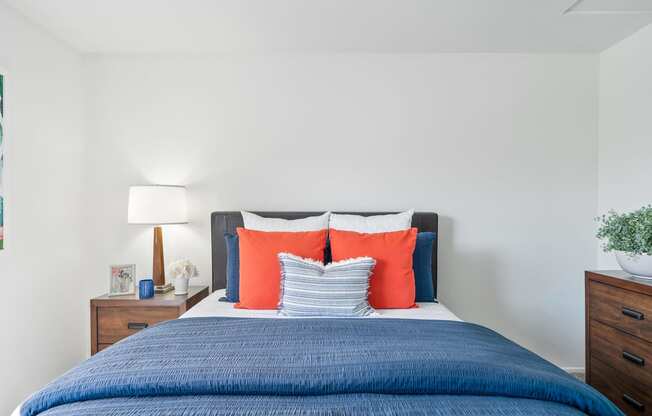 a bedroom with a blue bed and orange and blue pillows