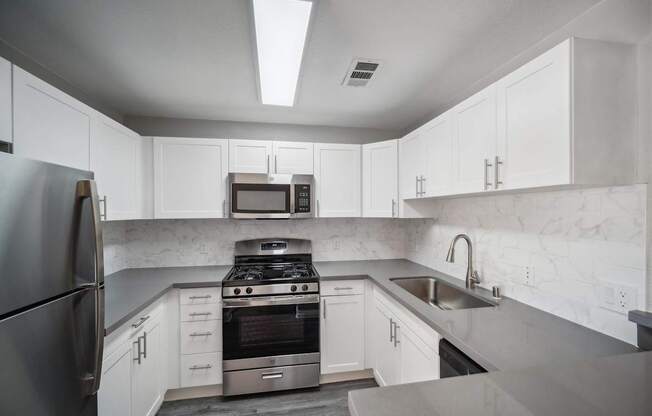 A modern kitchen with white cabinets and stainless steel appliances.