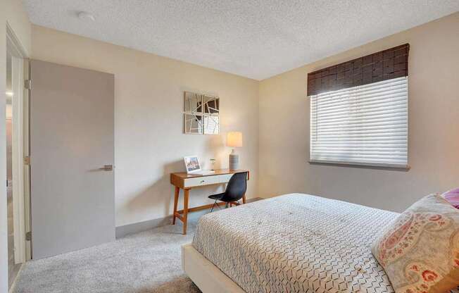 A bedroom with a bed, desk, and chair.