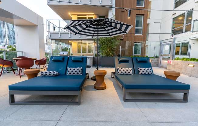 a seating area with blue couches and a black and white umbrella