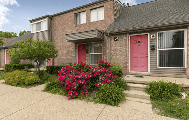 a pink door and pink flowers in front of a brick house