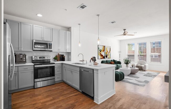 a kitchen with a large center island next to a living room with a couch and a window