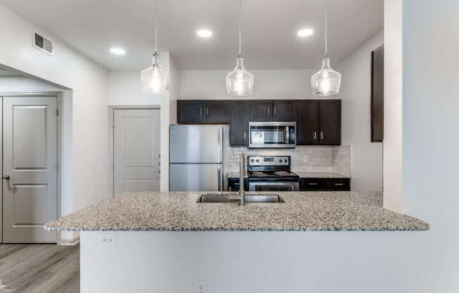 A kitchen with a granite countertop and a microwave above it.