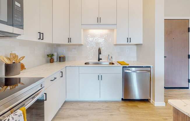 a kitchen with white cabinets and a stainless steel dishwasher