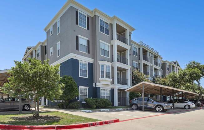 The exterior of the apartment complex with a parking lot in front at Encore at Buckingham Apartments in Richardson, TX