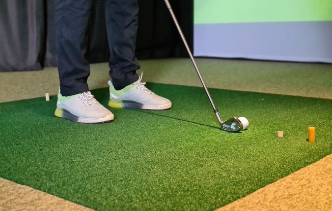 a golfer standing next to a golf ball on a putting green