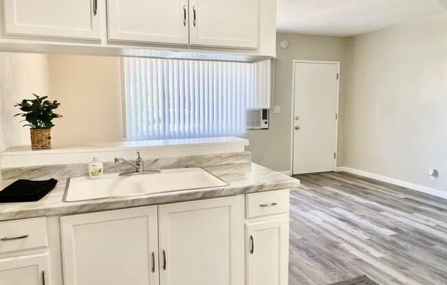 a kitchen with white cabinets and a white sink at South Pointe Apts, Covina