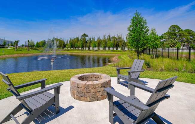 a patio with a fire pit and benches next to a pond at Altis Grand Lake Willis, Orlando, FL 32821