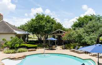 A pool surrounded by trees and a house.