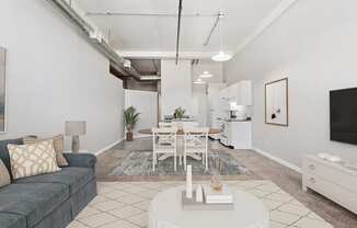A living room with a grey couch, a white coffee table, and a white dining table.