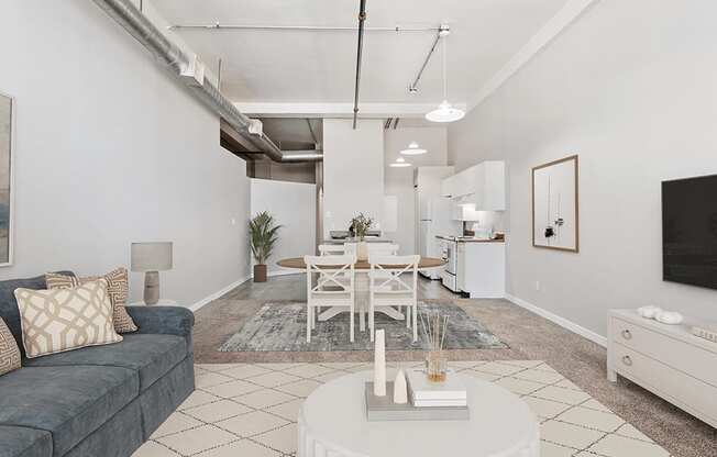 A living room with a grey couch, a white coffee table, and a white dining table.