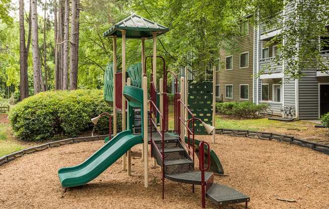 A playground with a green slide and a red and green play structure.