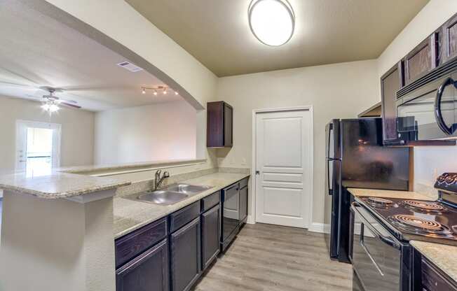 redesigned kitchen with granite countertops and stainless steel appliances and a door to the refrigerator