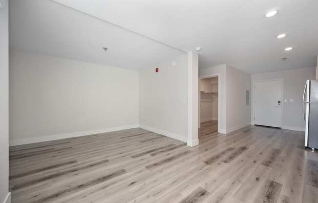 a living room with white walls and wood flooring and a refrigerator at Track 281 Apartments, Sacramento, 95811