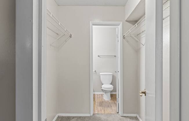 A white toilet is in a small bathroom with white walls and a white door.