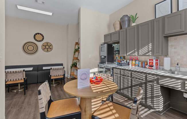 A kitchen area with a table and chairs and a counter with food on it.