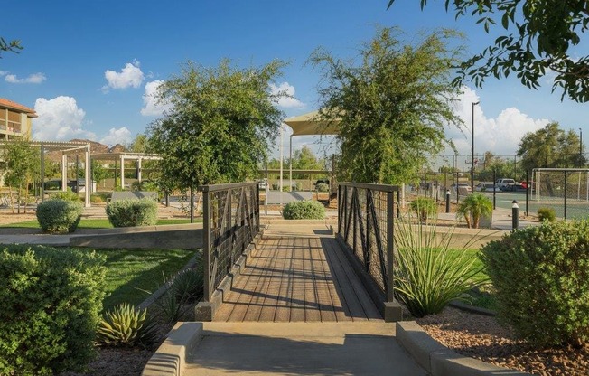 a bridge in a park with trees and a fence