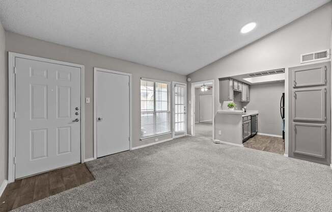 A spacious kitchen and living room with white appliances and a grey refrigerator.