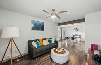 A living room with a grey couch and a wooden floor.