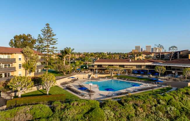 an aerial view of a resort with a pool and a city in the background