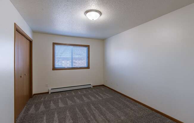 a bedroom with a window and closet. Fargo, ND Westwood Apartments