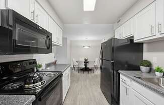 A modern kitchen with black appliances and white cabinets.
