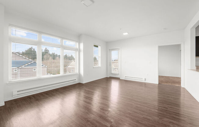 a bedroom with a large window and hardwood floors