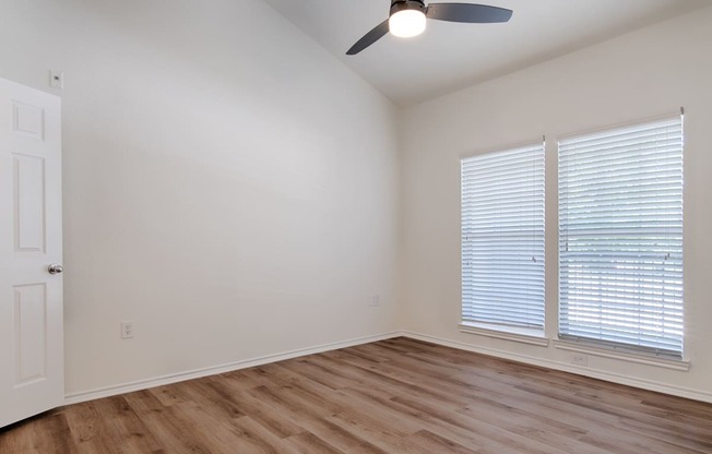 a bedroom with hardwood floors and a ceiling fan