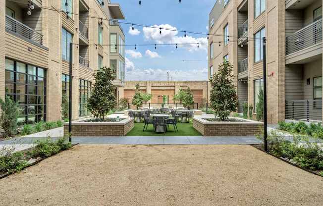 A courtyard surrounded by buildings with a table and chairs in the middle.