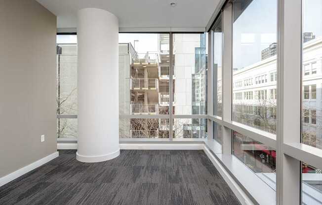 A room with a large white column and a view of the city through the windows.