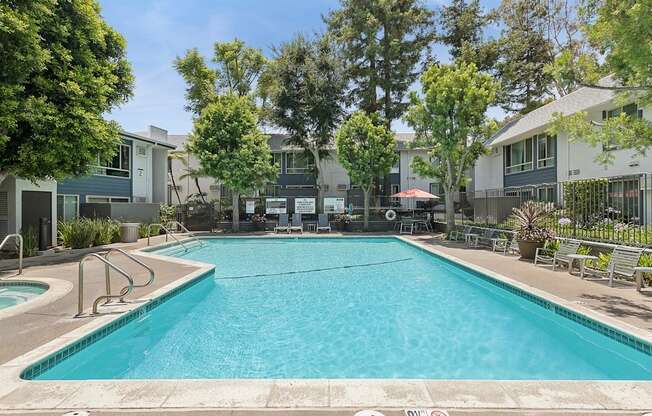 A large swimming pool surrounded by trees and apartment buildings.