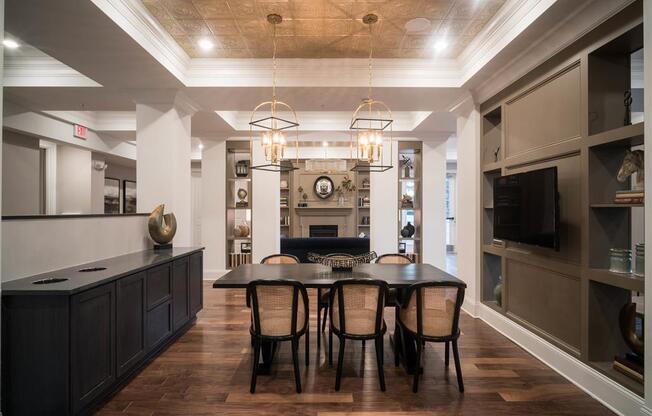 A dining area with woven-back chairs, chandeliers, and built-in shelving.