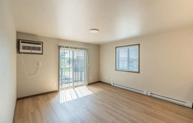 An empty living room with wood floors and a sliding glass door. Fargo, ND Granger Court Apartments