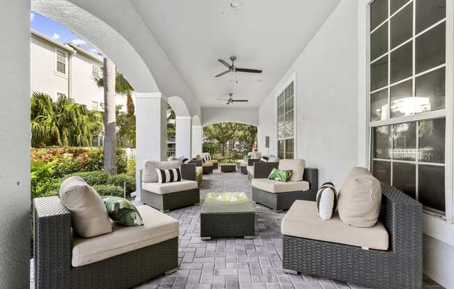 an outdoor patio with chairs and tables and a ceiling fan