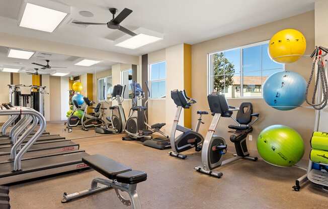 a gym with cardio equipment and exercise balls at the enclave at university crossings apartments