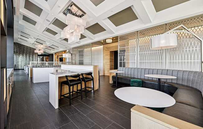 A modern dining area with a white counter and black chairs.