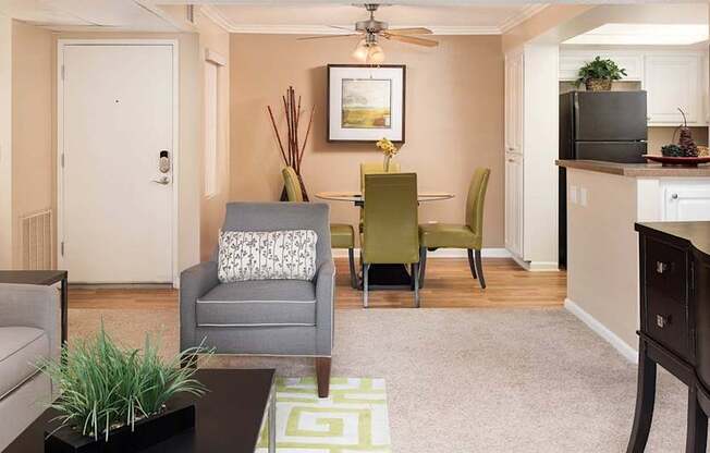 A living room with a grey couch, a green chair, a coffee table, and a flat screen TV.