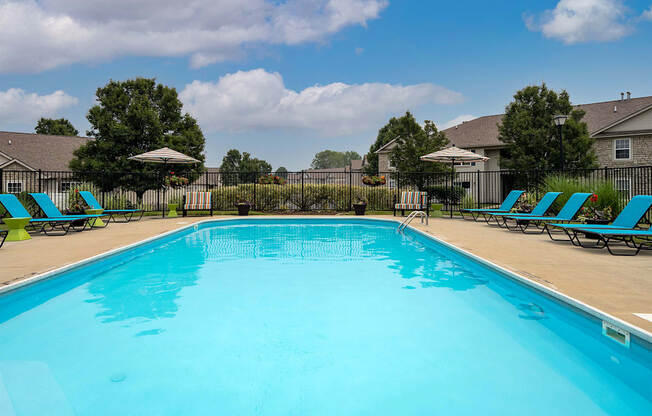 A large blue swimming pool with lounge chairs around it.