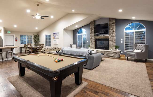 A pool table is in the middle of a room with a fireplace and a couch.