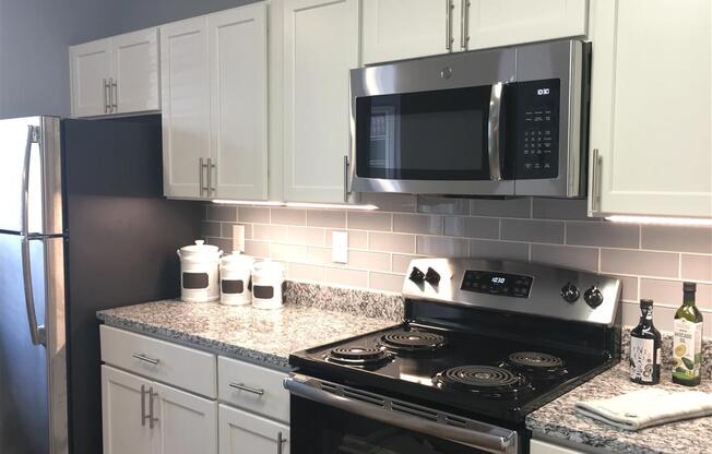 A kitchen with a black stove top oven and a black microwave above it. at Vue on Medlock, Peachtree Corners, Georgia