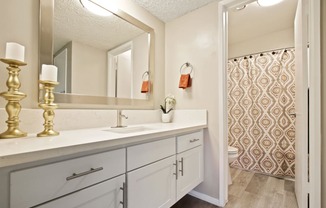 Long single vanity area with white quartz counter tops, white cabinet, bathroom on the right