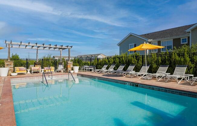 a swimming pool with chairs and a house in the background