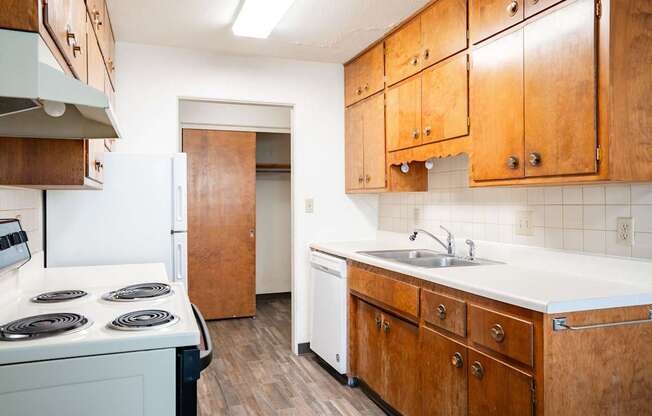 A kitchen with wooden cabinets and a white counter top. Fargo, ND Islander Apartments