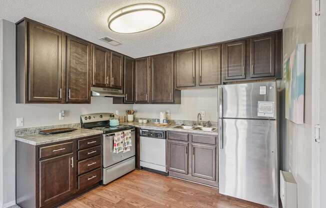 A kitchen with wooden cabinets and a refrigerator at The Falls Apartments in Raleigh NC