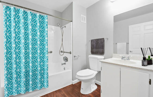 a bathroom with a white toilet next to a bathtub with a blue shower curtain