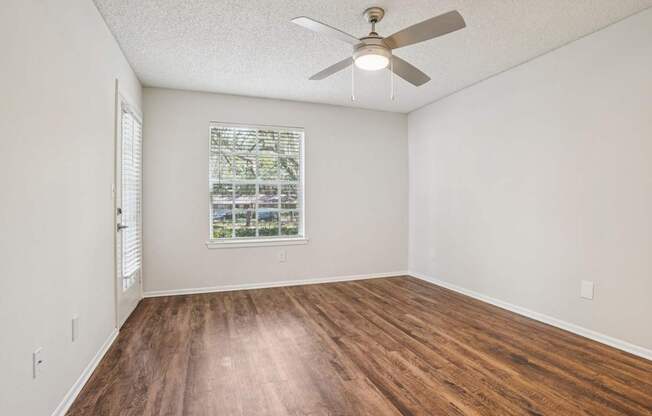 A room with a ceiling fan and a window with blinds.