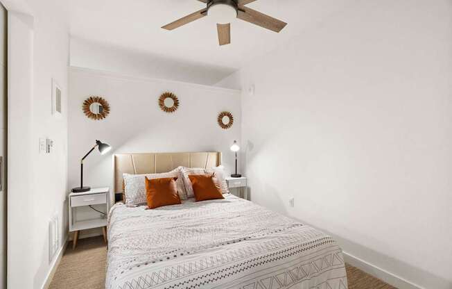 A bedroom with a bed, a ceiling fan, and wall decorations.