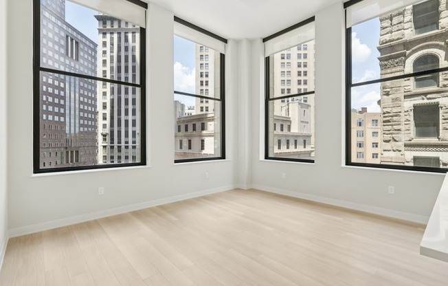A room with three large windows overlooking a cityscape.