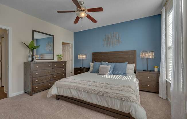 A bedroom with a large bed, a dresser, and a ceiling fan.